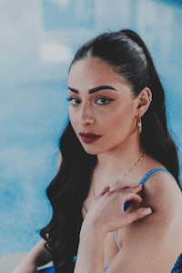 a woman in a blue swimsuit posing next to a pool